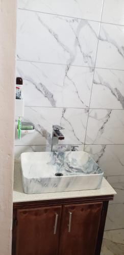 a white bathroom sink with a marble wall at Azille's Apt in Portsmouth