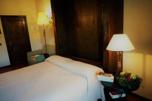 a bedroom with a large white bed and a lamp at Agriturismo Antico Borgo Poggitazzi in Loro Ciuffenna