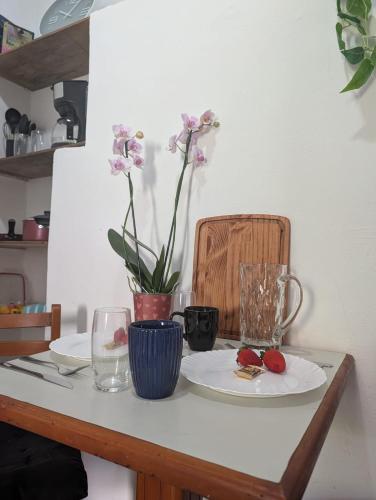 a table with plates and a vase with flowers on it at Acomodaçao Ipanema in Rio de Janeiro