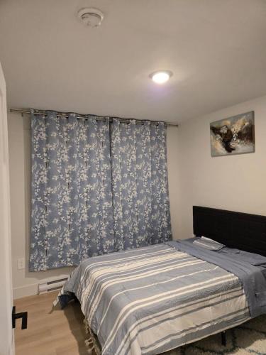 a bedroom with a bed and a blue and white curtain at Bournas Nest in Hammonds Plains