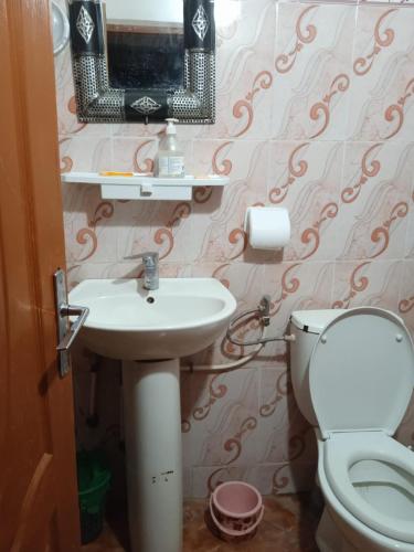 a bathroom with a sink and a toilet and a mirror at Maison du Bonheur berbère in Aït Ougliff