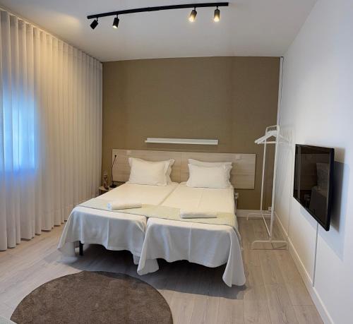 a bedroom with a large bed and a flat screen tv at Casa da Vila Guest House in Póvoa de Varzim