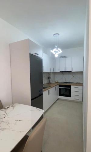 a kitchen with white cabinets and a table with chairs at Golem luxury apartment in Golem