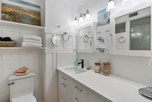 a white bathroom with a sink and mirrors at Pier Pointe #101 - 100 Floyd Street, Unit 101 in Saint Simons Island