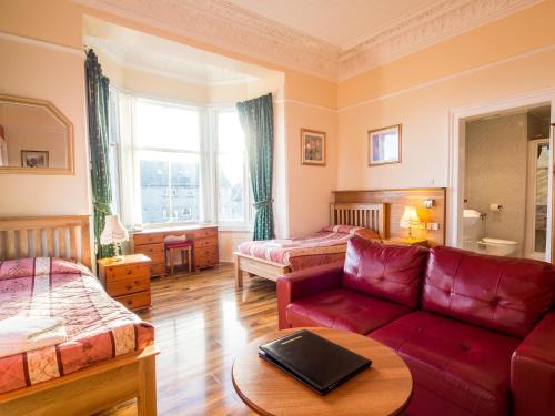 a living room with a red couch and a bed at Corstorphine Lodge Hotel in Edinburgh