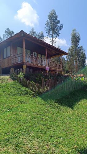 a large wooden house with a porch on a field at Cabaña Loto - Paipa in Paipa