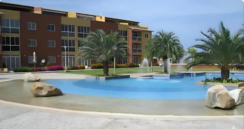 a large pool in front of a building with palm trees at Villa La Blanquilla in Pampatar