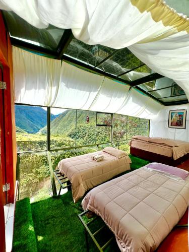 a room with three beds and a large window at Hanging Nest Salkantay in Colcapampa