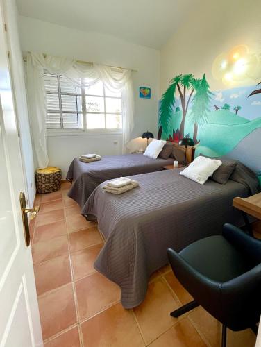 a bedroom with two beds and a palm tree mural at Casa Alegria in Puerto Rico de Gran Canaria