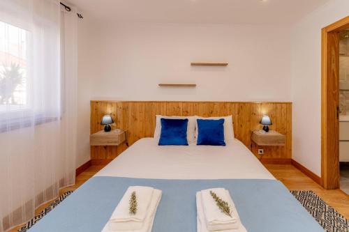 a bedroom with a large bed with blue pillows at LS Beach House in A dos Cunhados