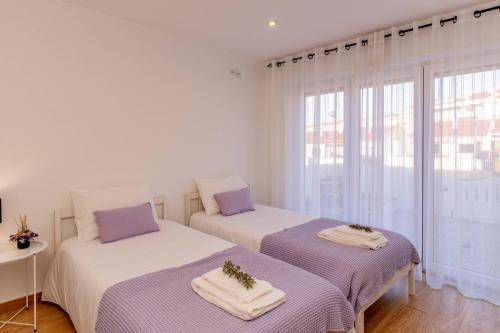 two beds in a white room with a window at LS Beach House in A dos Cunhados