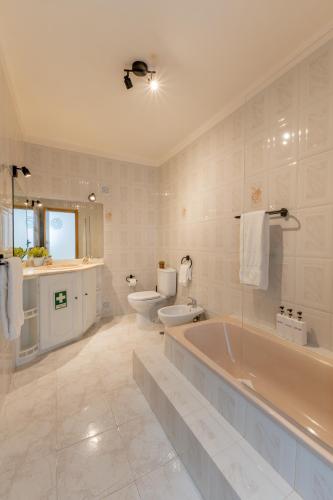 a bathroom with a tub and a toilet and a sink at LS Beach House in A dos Cunhados