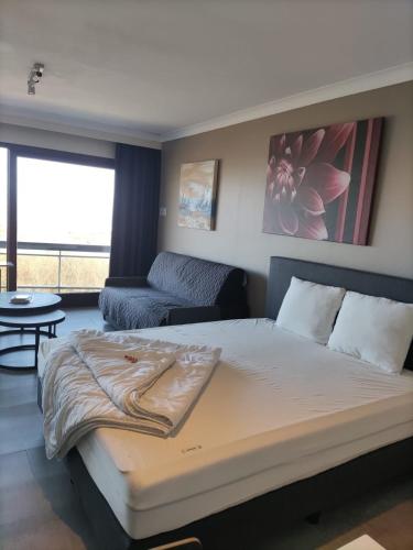 a bedroom with a large bed and a living room at Studio met zeezicht in Blankenberge