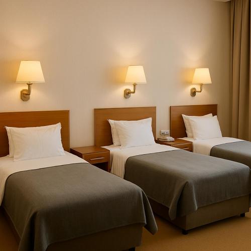 a hotel room with two beds and two lamps at El Mohandseen Cairo Hotel in Cairo