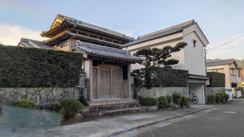 a house with a tree in front of it at くまの蔵 Kumanokura inn Storehouse in Shingū