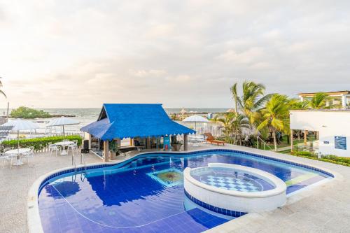 a swimming pool with a blue roof and the ocean at Hotel La Fragata Coveñas in Coveñas