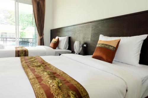 a hotel room with two beds and a window at The Oasis Khaolak Resort - SHA Plus in Khao Lak