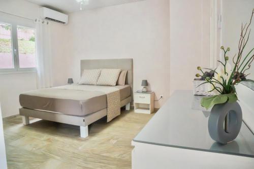 a white bedroom with a bed and a table at Villa avec piscine, vue sur mer, Rocher du Diamant in Sainte-Luce