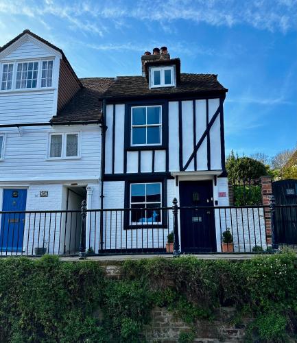 a white and black house with a fence at Romantic Boutique Cottage with pink roll-top bath-Hastings Old Town in Hastings