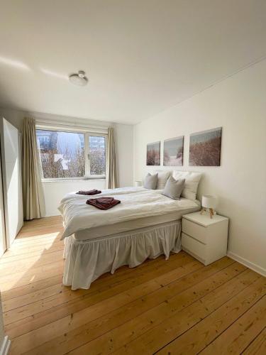 a white bedroom with a large bed and a window at Hyggelig, lys og centralt lejlighed in Esbjerg