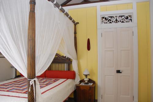 a bedroom with a canopy bed and a white door at House On The Path in Windward Side