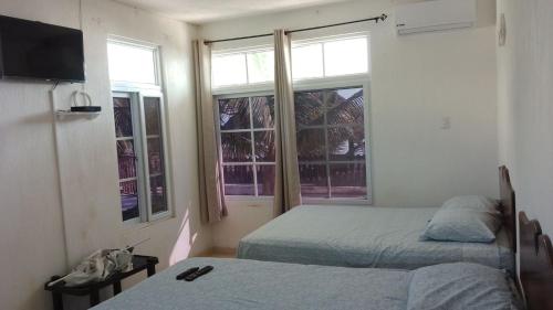 a bedroom with two beds and two windows at La casa de Fercho in Sipacate