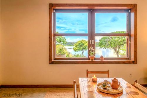a dining room table with a window with a view at Wafeh Pampulha Suítes in Belo Horizonte