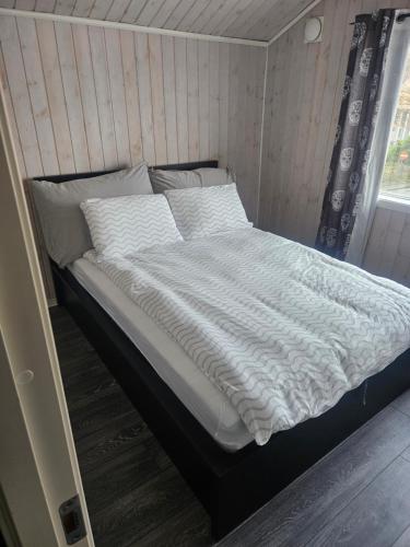 a bed with white sheets and pillows in a room at Koselig enebolig i Sentrum in Egersund
