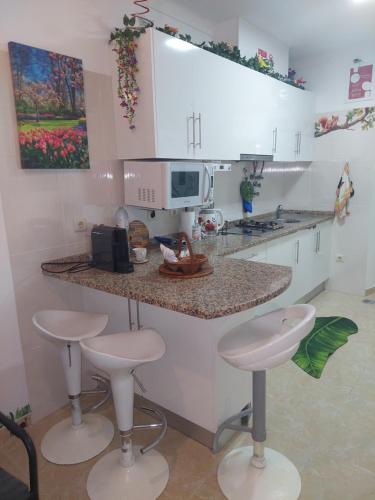 a kitchen with two stools and a counter with a microwave at Ketchs House in Ponte de Sor