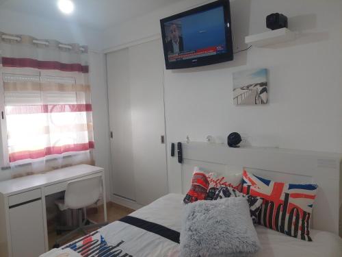 a bedroom with a bed with a television on the wall at Ketchs House in Ponte de Sor