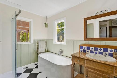 a bathroom with a tub and a sink and a mirror at Sanctuary Cottage in Karapiro