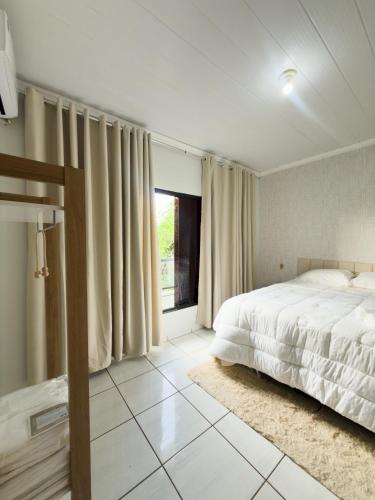 a bedroom with a bed and a large window at Apartamento Super Conforto in Naviraí