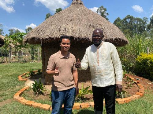 two men are standing in front of a hut at Del Mar Tour Camp - Kenya in Busia
