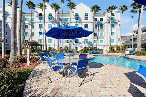 a table with chairs and an umbrella next to a pool at Pool View DisneyUniversalFree ShuttleParking in Orlando