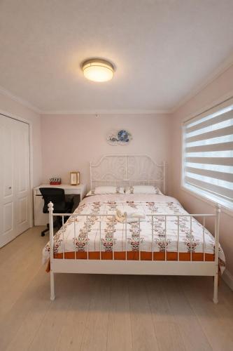 a bedroom with a white bed and a desk at Private Suite in a Friendly Shared Home in Vancouver