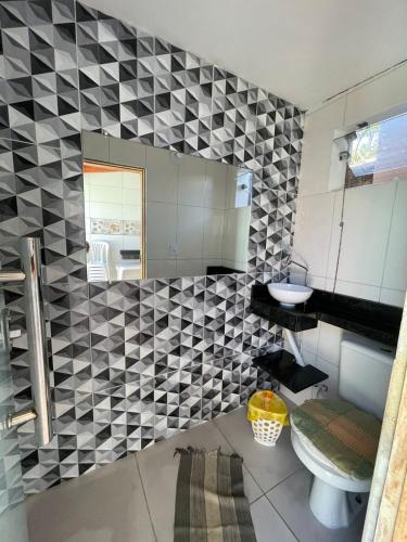 a bathroom with a black and white tiled wall at Casa com Piscina em Prado Bahia in Prado