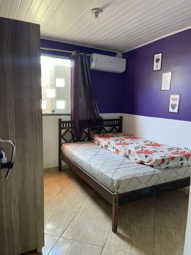 a small bed in a room with a purple wall at Casa com Piscina em Prado Bahia in Prado
