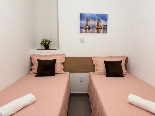 two beds in a small room with pink sheets at Voer Jequitibá Hospedaria in Jequitibá