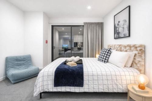 a bedroom with a bed and a blue chair at Fitzgerald Focus - Your 1BR Urban Oasis in Christchurch