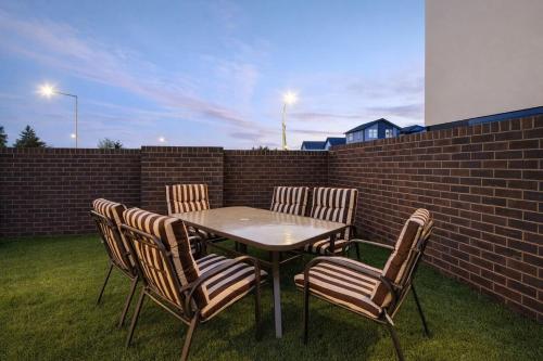 a table with four chairs and a brick wall at Fitzgerald Focus - Your 1BR Urban Oasis in Christchurch