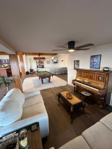 a living room with a couch and a piano at Cabaña con Piscina para Descansar in Chihuahua