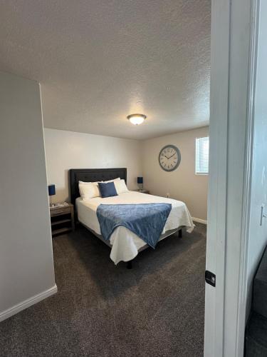 a bedroom with a bed with a clock on the wall at Cozy Apt in Downtown Logan in Logan