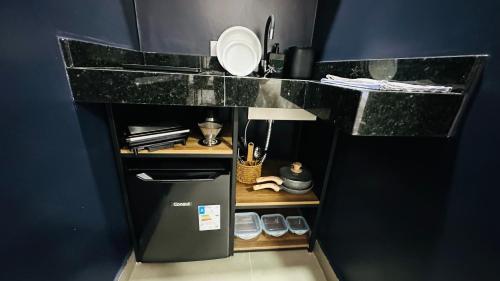 a kitchen with a black counter top with slippers on a shelf at Chacara Stay in São Paulo