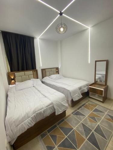 a bedroom with two beds and a mirror in it at سكن فندقى باكتوبر in Al Kawāmil Qiblī