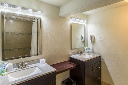 a bathroom with two sinks and a mirror at Clarion Inn near McAllen Airport in McAllen
