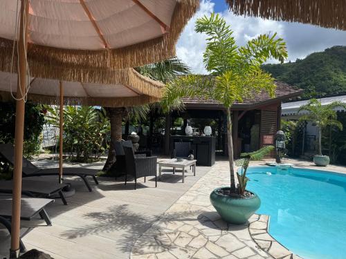 a pool with chairs and umbrellas next to a resort at Relais Fenua in Punaauia