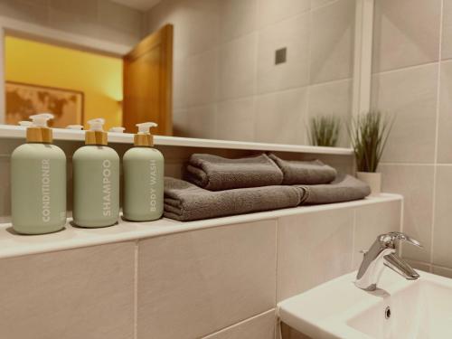 a bathroom with three bottles on a shelf next to a sink at Cardiff City Center - FREE On-Site Parking in Cardiff