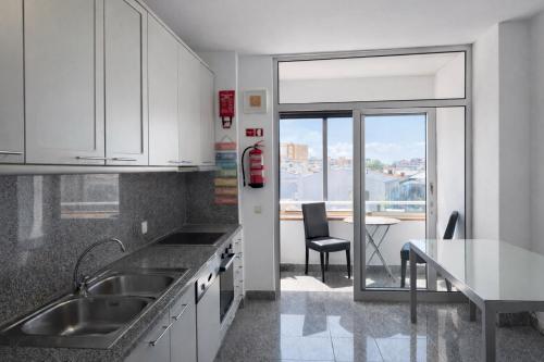 a kitchen with a sink and a table with a chair at Free Wave Rooms in Maia