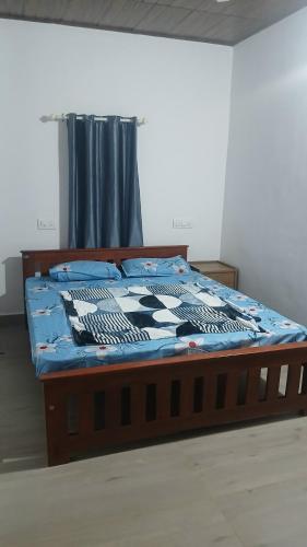 a bed with a blue and white comforter in a room at Kanthanpara mist stay in Meppādi