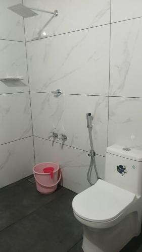 a bathroom with a white toilet and a pink bucket at Kanthanpara mist stay in Meppādi